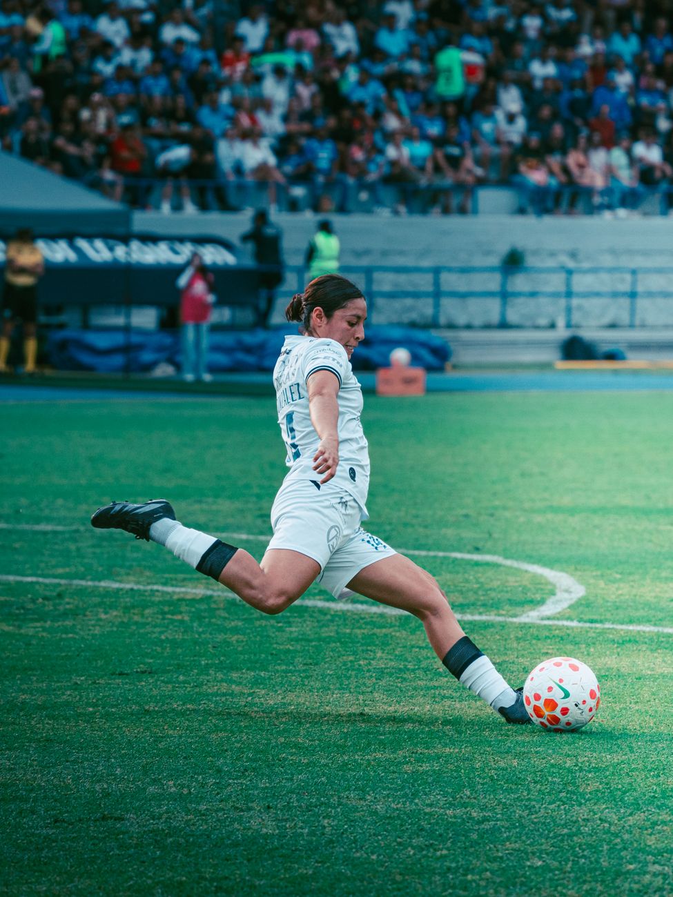 female soccer player kicking ball in stadium